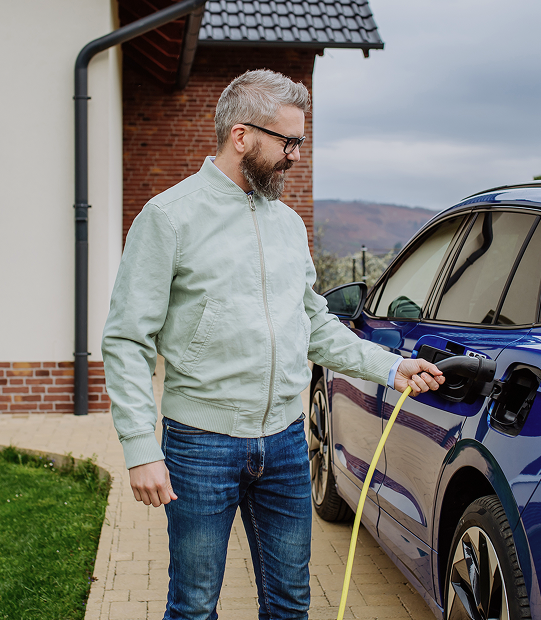 Man charging electric vehicle at home