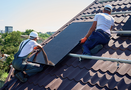 Team of solar installers fitting a solar panel to a roof