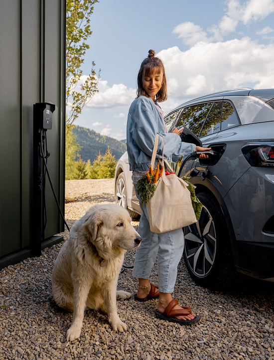 Woman & their dog waiting while they charge an EV