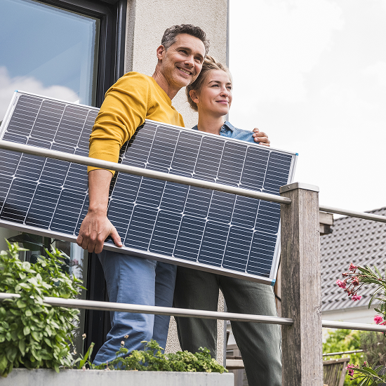 Man holding solar panel smiling while hugging a woman