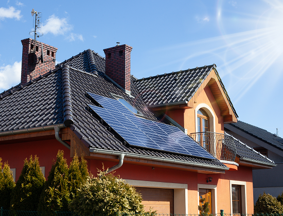 Residential home with solar panels on the front of the house's roof while the sun shines bright powering the panels