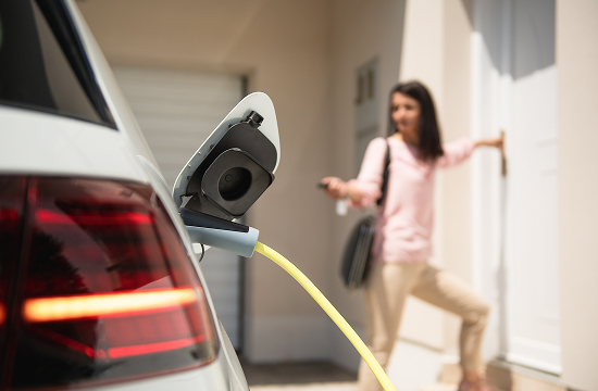 Woman walking into her home after plugging in EV to wall charger
