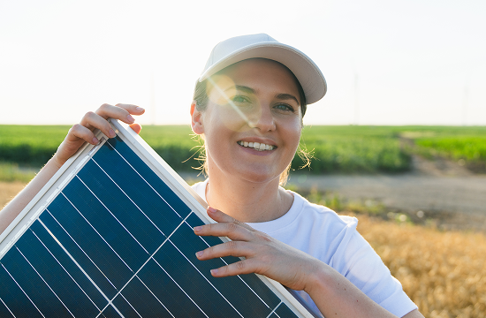 Smiling woman holding solar panel on a rural residential property